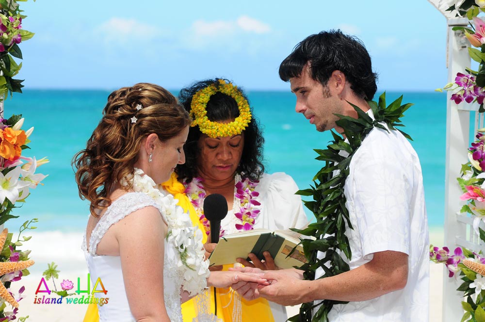 Minister Leihulu Mamo reading the vows to a couple under a flower arch
